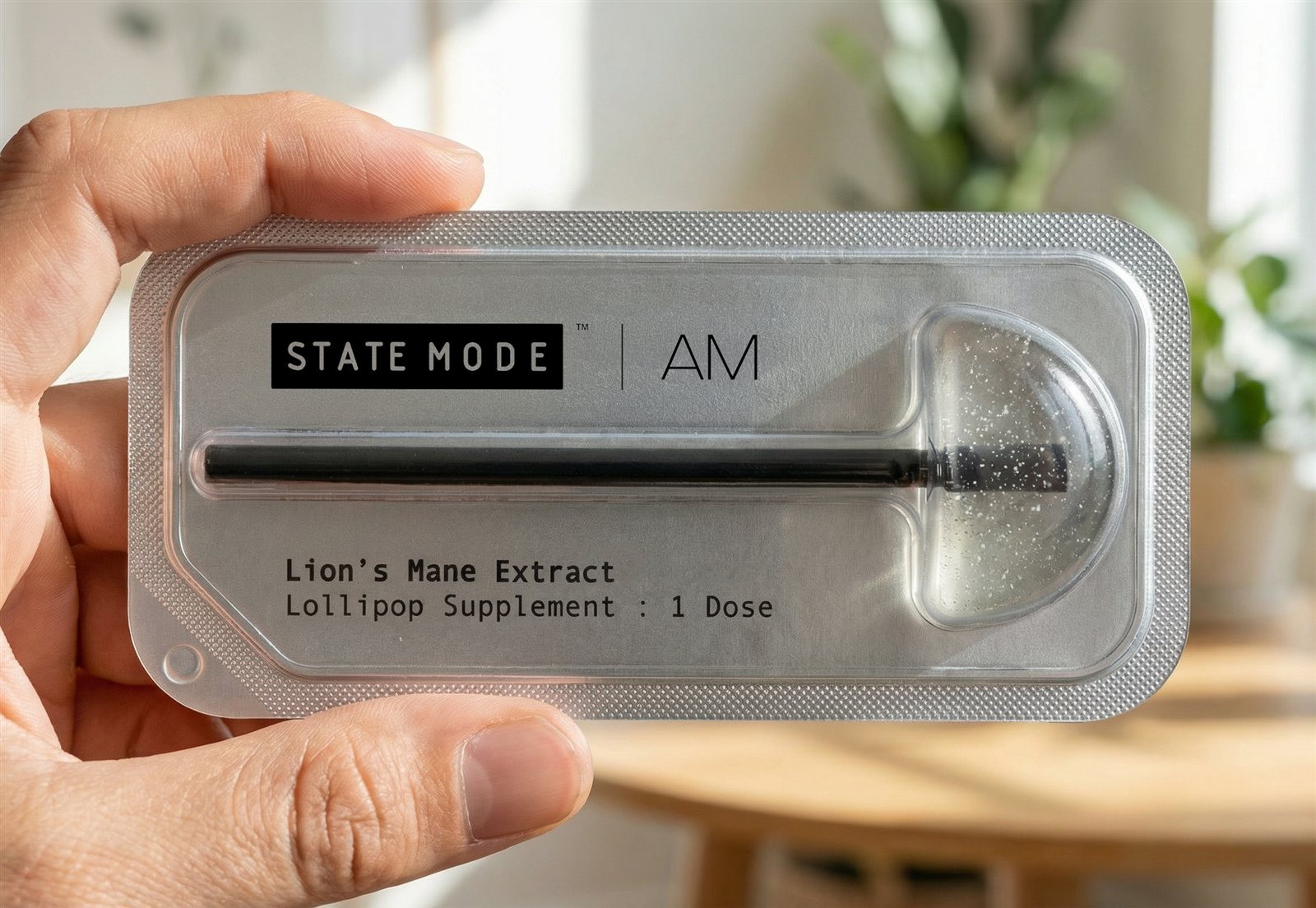 Hand holding a State Mode AM Lion's Mane lollipop supplement